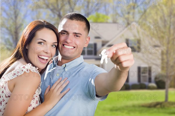 mixed-race excited military couple in front of new home showing off their house keys