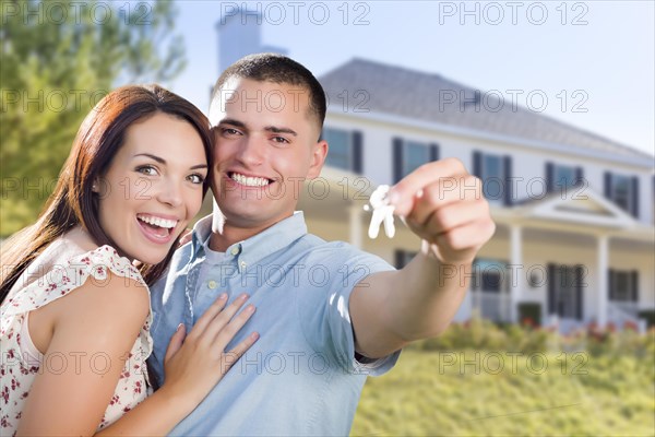 mixed-race excited military couple in front of new home showing off their house keys