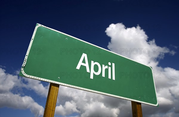 April green road sign with dramatic blue sky and clouds