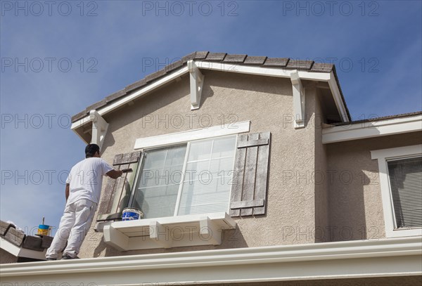 Busy house painter painting the trim and shutters of A home