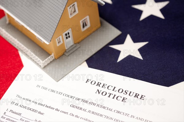 Foreclosure notice and house on the american flag with selective focus