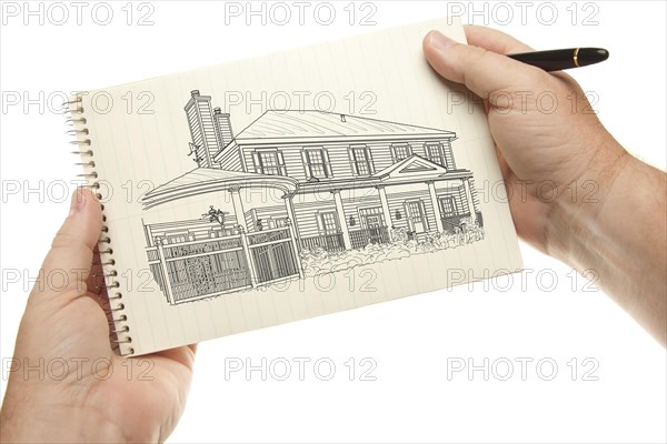 Male hands holding pen and pad of paper with house drawing isolated on a white background