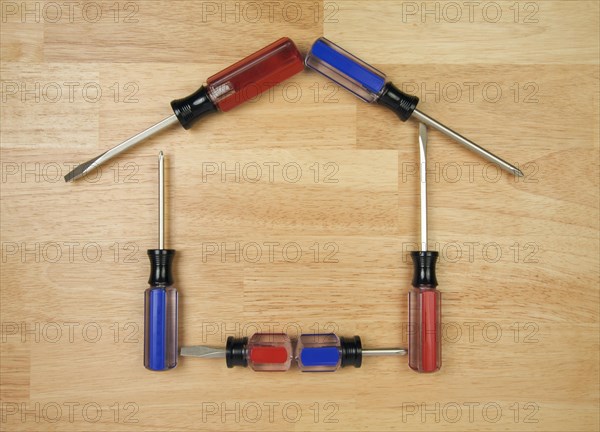 House shaped by screwdrivers on a wood background