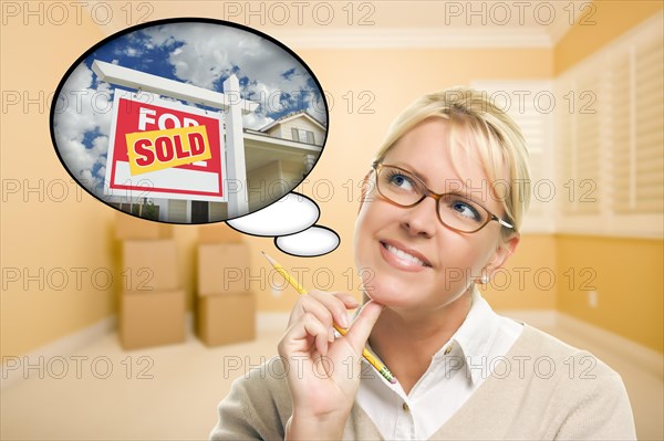 Attractive woman in empty room with thought bubble of a sold for sale real estate sign in front of house
