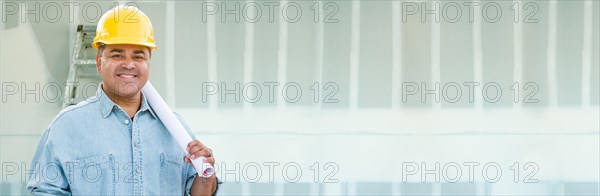 Hispanic male contractor wearing hard hat against drywall banner background with ladder