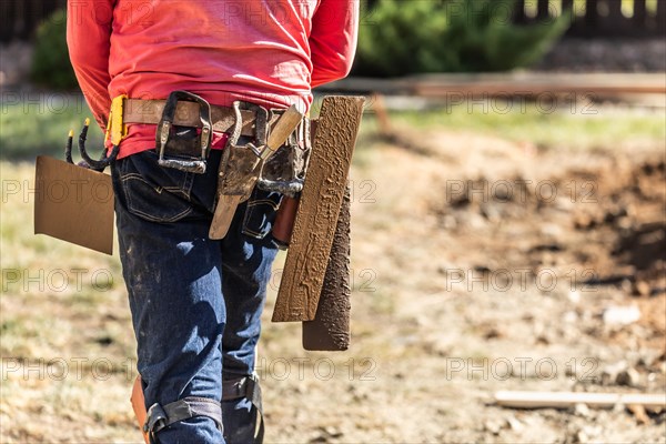 Cement construction worker with toolbelt holding various trowels and tools on belt