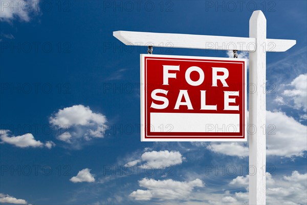 Left facing for sale real estate sign over blue sky and clouds with room for your text