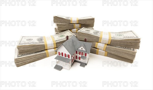 Small house with stacks of hundred dollar bills isolated on a white background