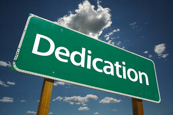 Dedication green road sign with dramatic clouds and sky