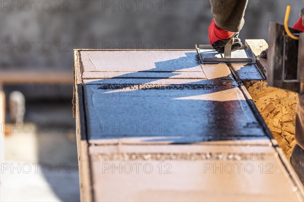 Construction worker using hand groover on wet cement forming coping around new pool