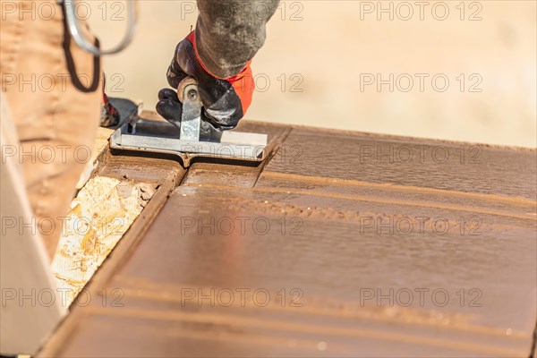 Construction worker using hand groover on wet cement forming coping around new pool