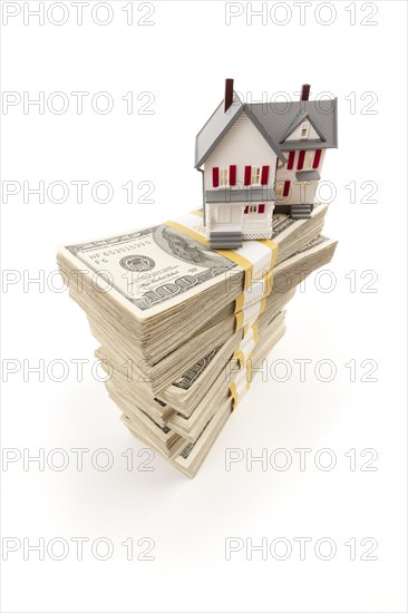 Small house on stacks of hundred dollar bills isolated on a white background