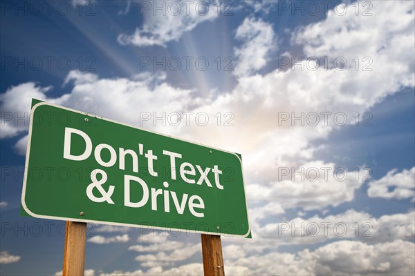 Don't text and drive green road sign with dramatic sky