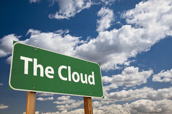 The cloud green road sign over clouds and sky