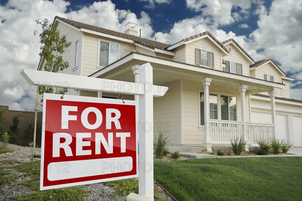 Right facing red for rent real estate sign in front of beautiful house