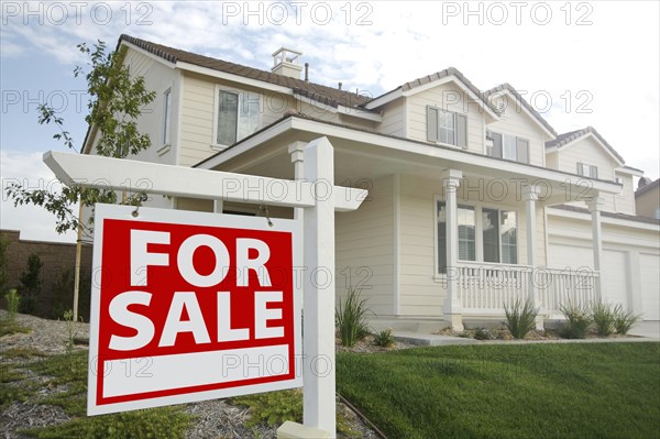 For sale real estate sign in front of beautiful new home