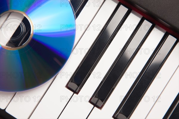 CD laying on piano keyboards abstract