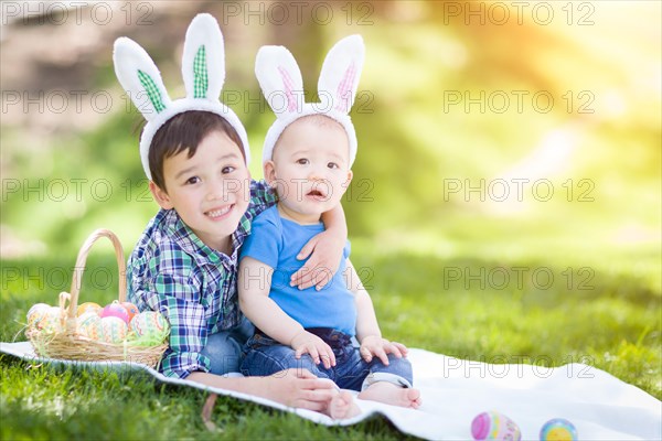 mixed-race chinese and caucasian boys outside in park playing with easter eggs