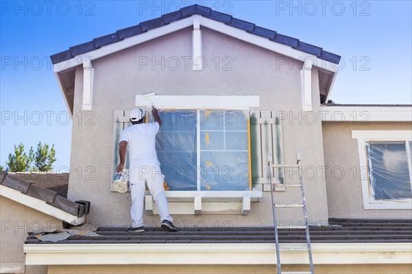 Busy house painter painting the trim and shutters of A home