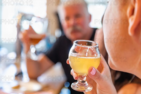 Female sipping glass of micro brew beer at bar with friends