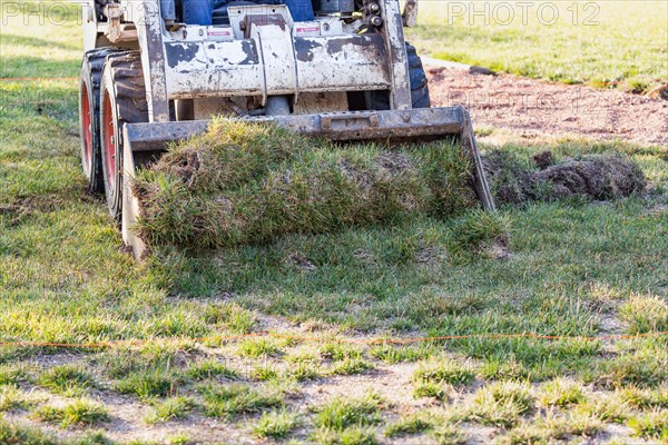 Small bulldozer removing grass from yard preparing for pool installation