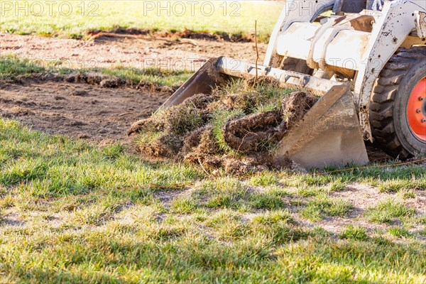 Small bulldozer removing grass from yard preparing for pool installation