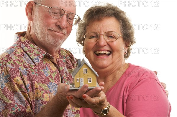 Happy senior couple holding a model home