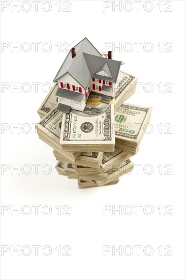 Small house on stacks of hundred dollar bills isolated on a white background