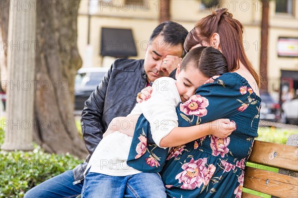 Caucasian mother and hispanic father comforting mixed-race son outdoors