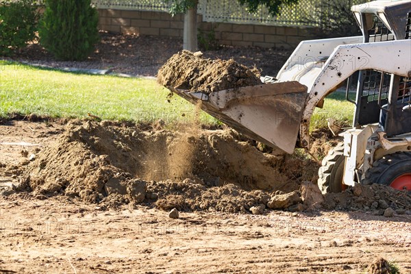 Small bulldozer digging in yard for pool installation