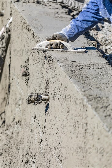 Pool construction worker working with wood float on wet concrete