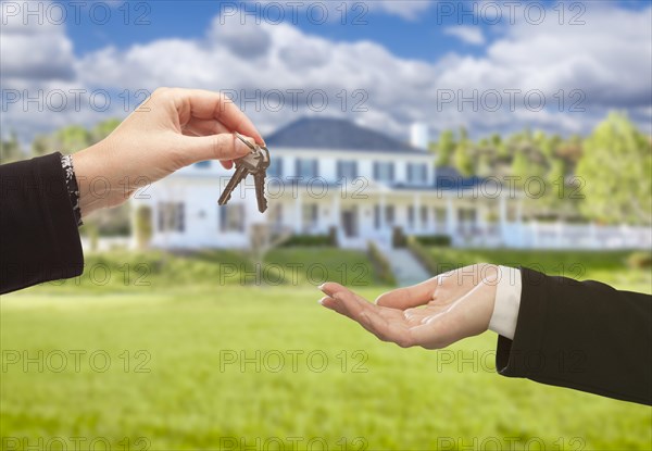 Real estate agent handing over the house keys in front of a beautiful new home