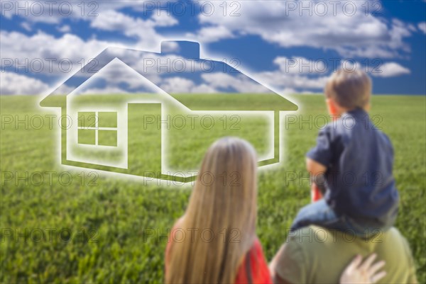 Young family in grass field with ghosted house in front of them