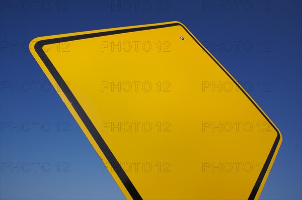Blank yellow road sign against a dramatic blue sky with clipping path