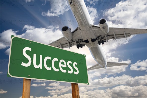 Success green road sign and airplane above with dramatic blue sky and clouds