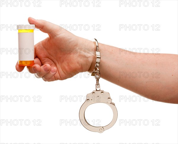 Handcuffed man holding blank medicine bottle isolated on a white background