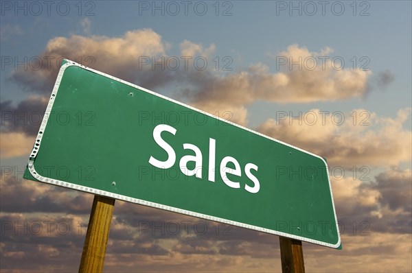 Sales green road sign with dramatic clouds and sky