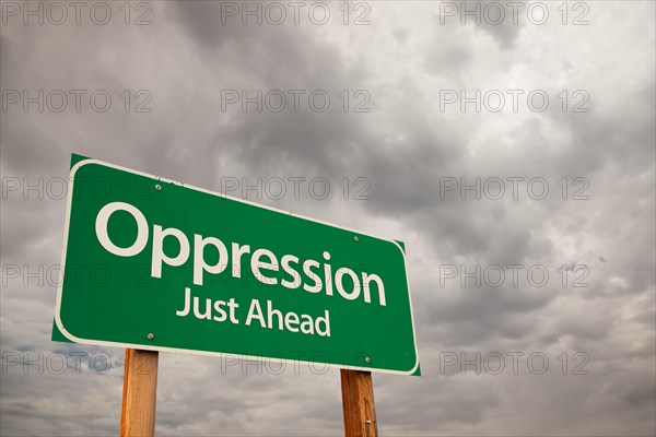 Oppression just ahead green road sign with dramatic storm clouds and sky