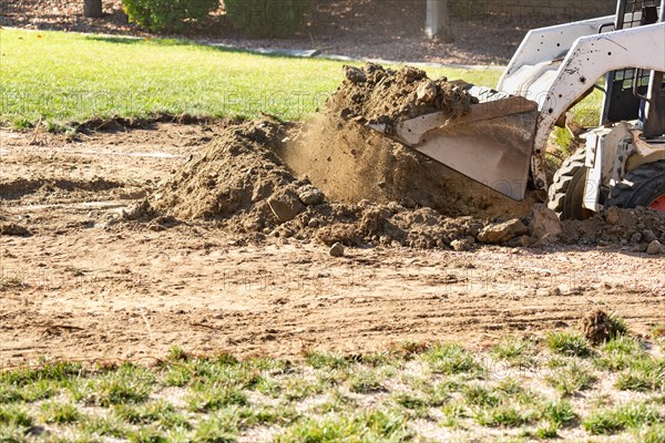 Small bulldozer digging in yard for pool installation