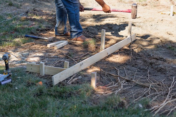 Worker installing stakes and lumber guides at construction site