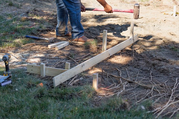 Worker installing stakes and lumber guides at construction site