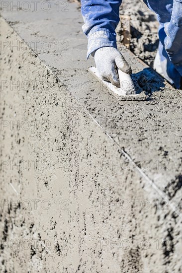 Pool construction worker working with wood float on wet concrete