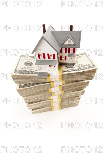 Small house on stacks of hundred dollar bills isolated on a white background