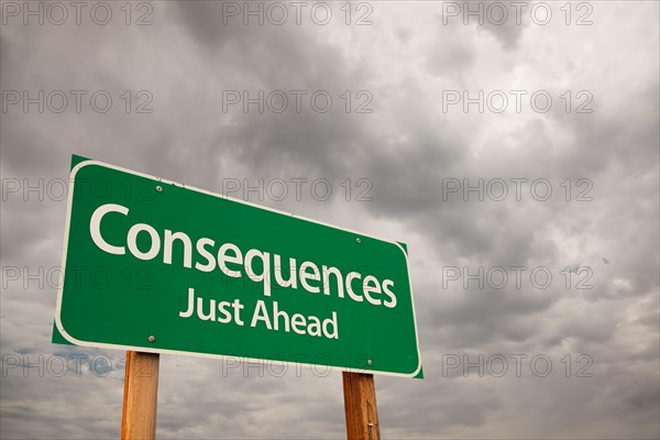 Consequences just ahead green road sign with dramatic storm clouds and sky