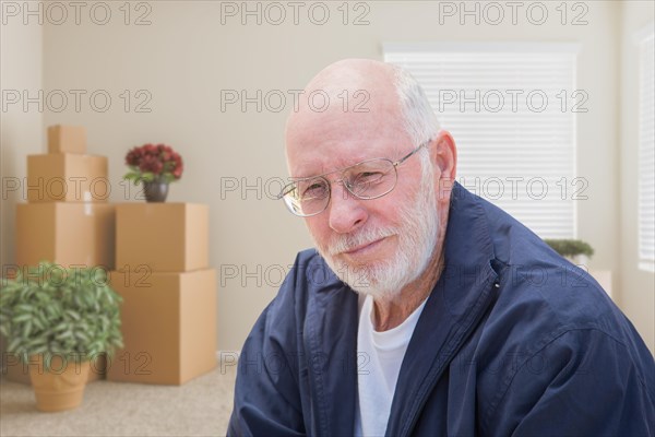 Senior man in empty room with packed moving boxes