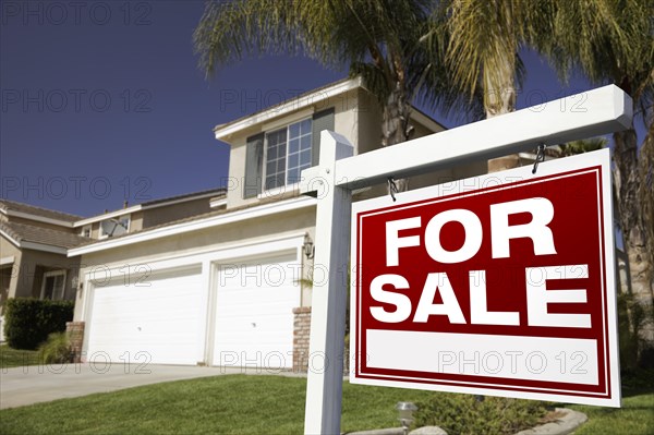 For sale real estate sign in front of house