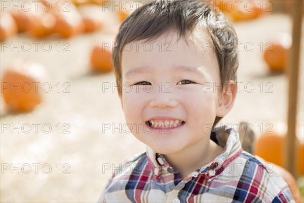 Cute mixed-race young boy having fun at the pumpkin patch