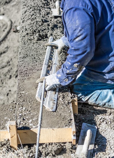 Pool construction worker working with A smoother rod on wet concrete