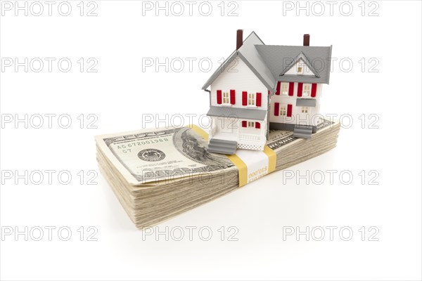 Small house on stack of hundred dollar bills isolated on a white background