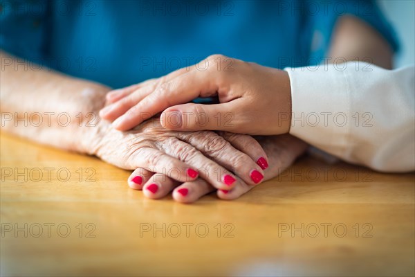 Younger female hands holding senior adult woman hands